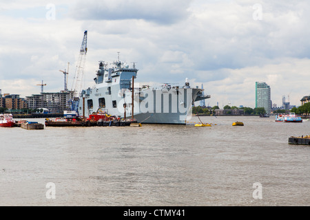 Le HMS Ocean amarré à Greenwich avec la ville de Londres derrière elle Banque D'Images