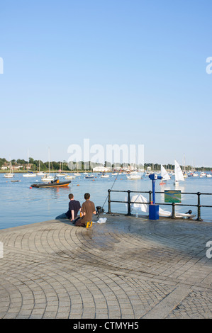 Deux jeunes hommes assis sur le quai à Hamble Marine en Hampshire UK Banque D'Images