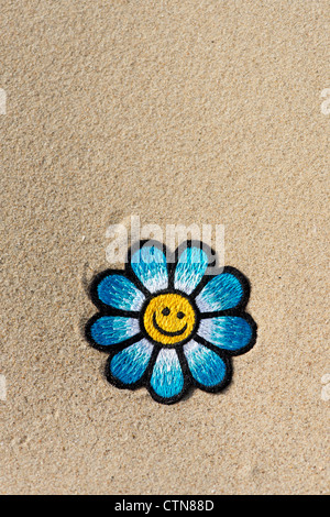 Broderie multicolore sur fer flower patch Smiley en sable d'une plage Banque D'Images