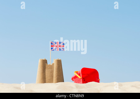 Union Jack flag dans un château de sable à côté d'un seau et d'une bêche sur une plage. Wells next the sea. Norfolk, Angleterre Banque D'Images