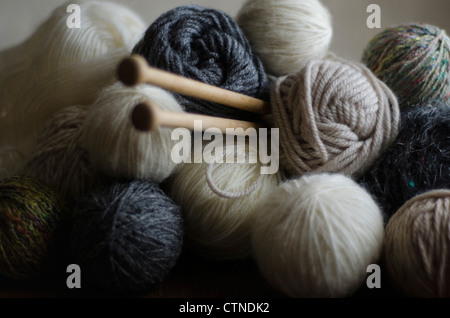 Close up de balles de laine d'agneau coupé en tons de blanc, gris et beige avec des aiguilles à tricoter en bois Banque D'Images