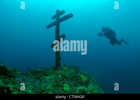 Le plongée sous-marine regarde une grande croix montée sur un rocher sous-marin dans le lac Baikal Banque D'Images