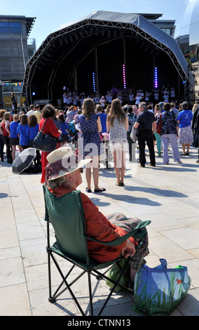 Concert en plein air devant un auditoire à Bristol la Place du Millénaire avec les anciens woman sitting in chair Banque D'Images