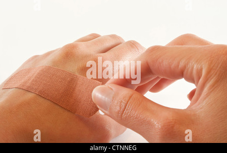 Coller la main féminine pansement ou bandage sur une coupe de l'autre main. Banque D'Images