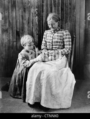 Prévision - une vieille femme assis sur une chaise avec peler une jeune fille, peut-être une petite-fille, à genoux sur le sol à côté d'elle, regarder, vers 1897 Banque D'Images