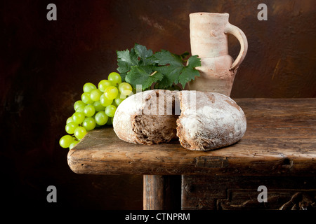 Meubles anciens cruche de vin avec des raisins et du pain consacré Banque D'Images