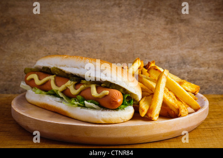 Hot dog avec frites sur une plaque de bois Banque D'Images