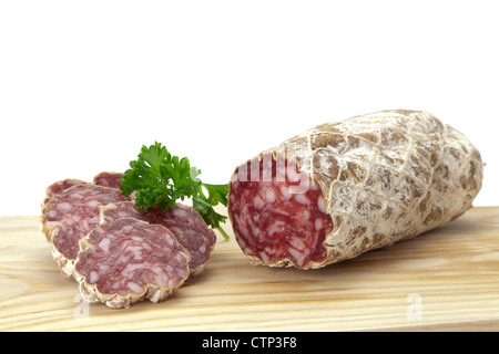 Une salaison à sec en tranches de salami saucisses sur une planche à découper en bois - studio photo avec un fond uni Banque D'Images