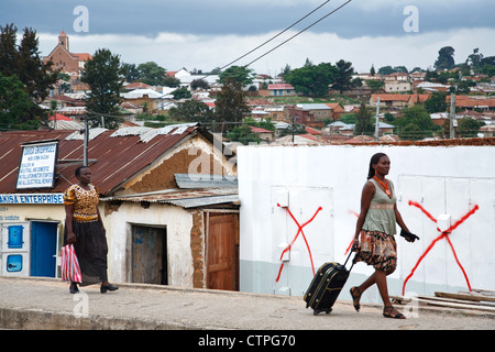 Scène de la vie quotidienne à Iringa, Tanzanie, Afrique. Deux femmes marchant dans la rue avec une chaussée du panorama vu de la ville. Banque D'Images