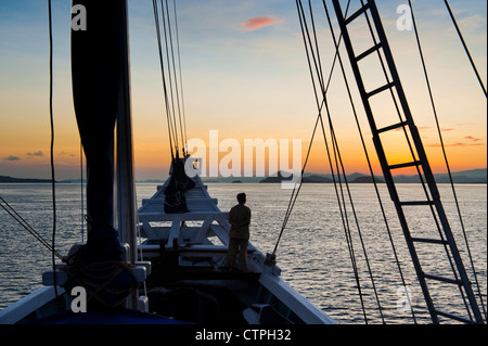 Lever du soleil à bord du 108 'pied Ombak Putih", une goélette Phinisi traditionnel cruising dans la région de Nusa Tenggara en Indonésie. Banque D'Images