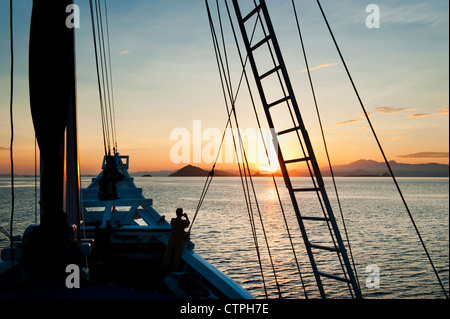 Lever du soleil à bord du 108 'pied Ombak Putih", une goélette Phinisi traditionnel cruising dans la région de Nusa Tenggara en Indonésie. Banque D'Images