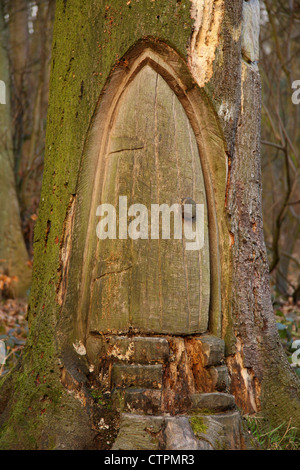 La sculpture sur bois de petite porte en base d'arbre, Derbyshire, . Cela pourrait-il être le domicile d'un hobbit ? Banque D'Images