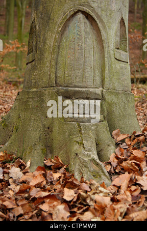 La sculpture sur bois d'une petite porte dans la base d'arbre entouré par les feuilles d'automne, Derbyshire, Royaume-Uni Banque D'Images