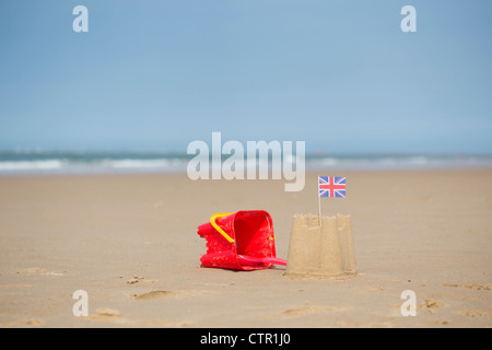 Union Jack flag dans un château de sable à côté d'un seau et d'une bêche sur une plage. Wells next the sea. Norfolk, Angleterre Banque D'Images