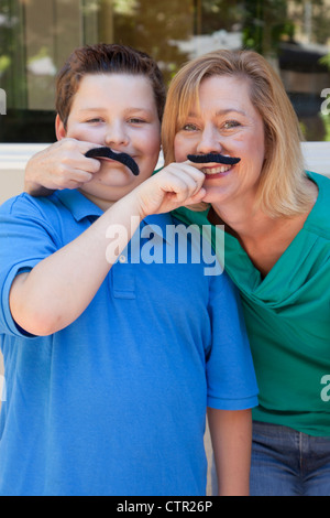 Mère et fils jouent avec de fausses moustaches. Banque D'Images