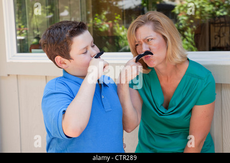 Mère et fils jouent avec de fausses moustaches. Banque D'Images