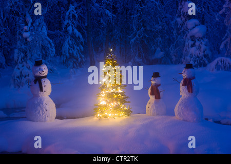 La famille bonhomme debout à côté arbre de Noël sur l'île couverte de neige au petit ruisseau dans la forêt couverte de givre twilight Banque D'Images