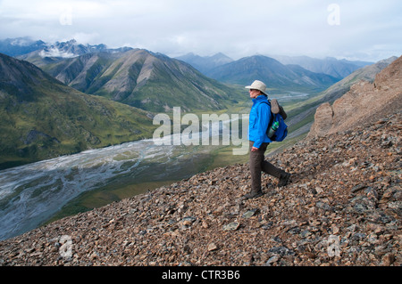 Mature female hiker descend au-dessus de la crête de Marsh Fork Canning River dans Brooks Arctic National Wildlife Refuge en Alaska Summer Banque D'Images