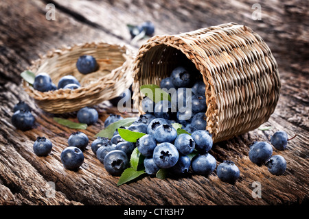 Les bleuets ont chuté à partir du panier sur une vieille table en bois. Banque D'Images