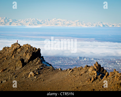 Femme Trail Runner se dresse sur une crête rocheuse au-dessus de l'Alaska Anchorage au-delà des montagnes Chugach, Southcentral Alaska Autumn Banque D'Images