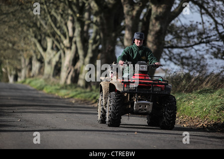 Agriculteur sur quad avec son chien à l'arrière Banque D'Images