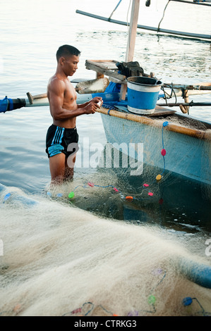 Un pêcheur dans le village balinais de Pemuteran, dans le nord-ouest de Bali décharge ses prises sur la plage après une nuit de pêche. Banque D'Images