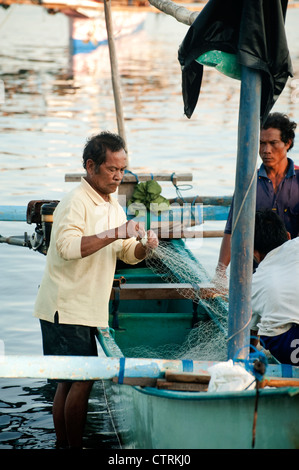 Un pêcheur dans le village balinais de Pemuteran, dans le nord-ouest de Bali décharge ses prises sur la plage après une nuit de pêche. Banque D'Images