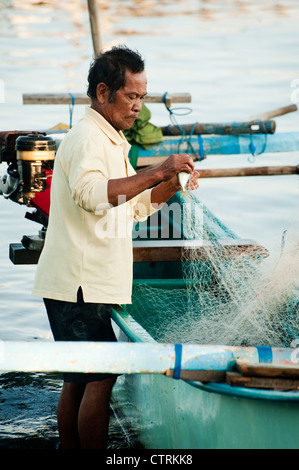 Un pêcheur dans le village balinais de Pemuteran, dans le nord-ouest de Bali décharge ses prises sur la plage après une nuit de pêche. Banque D'Images