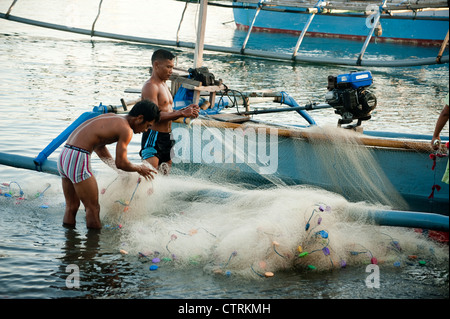 Un pêcheur dans le village balinais de Pemuteran, dans le nord-ouest de Bali décharge ses prises sur la plage après une nuit de pêche. Banque D'Images