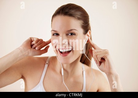 Une jeune femme portant des vêtements fitness et écouteurs, smiling at camera Banque D'Images