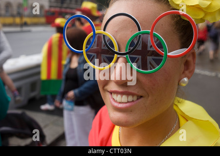 Portant des lunettes, un anneau olympique dame fan de sport tours centre de Londres lors d'une pause en regardant les événements au cours de l'Jeux olympiques de 2012 à Londres. Vêtus de leurs couleurs nationales du pays les amis profitez d'un répit des pluies d'été à marcher à travers les rues de la capitale. Banque D'Images