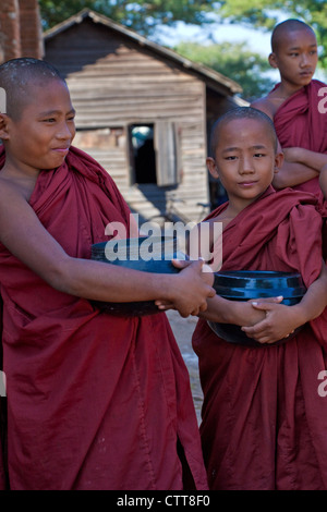 Le Myanmar, Birmanie. Bagan. Les jeunes moines novices tenant leurs bols mendicité. Banque D'Images