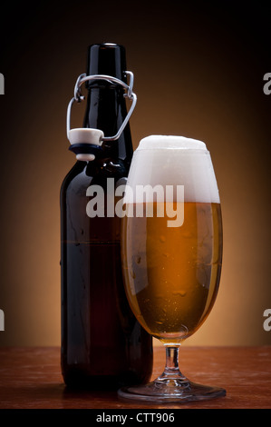 Verre et bouteille de bière bien fraîche sur une table en bois Banque D'Images