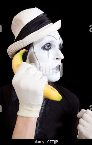 Mime dans white hat holding une banane dans sa main close up Banque D'Images