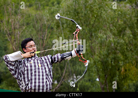 Un archer en robe bhoutanais traditionnel prend part à un concours de tir à l'arc à Thimphu, Bhoutan Banque D'Images