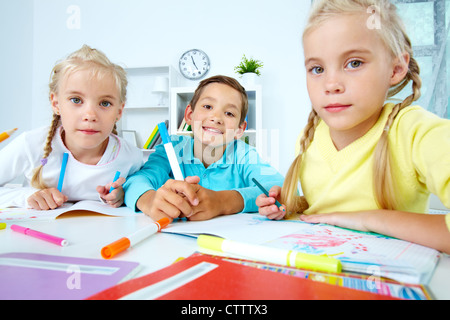 Smart schoolboy et twin girls looking at camera Banque D'Images