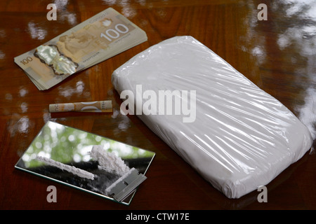 Grand sac de cocaïne drogue avec les billets de cent dollars de l'argent en espèces et la ligne de coke avec une lame de rasoir sur la table Banque D'Images
