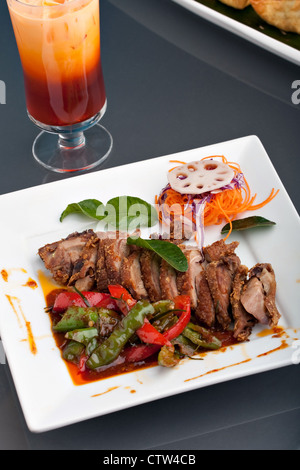 Très bien présenté un plat de style Thaï chili rôti de canard au basilic thaï et un mélange de légumes avec le thé glacé. Banque D'Images