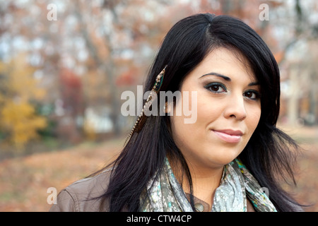 Belle jeune femme hispanique portant des extensions de cheveux en plumes personnalisées dans ses cheveux noirs. Banque D'Images