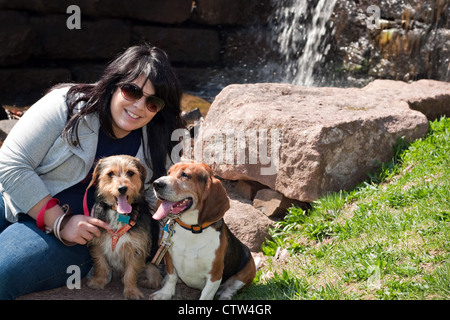 Une jeune femme pose avec ses deux chiens par une cascade. Banque D'Images