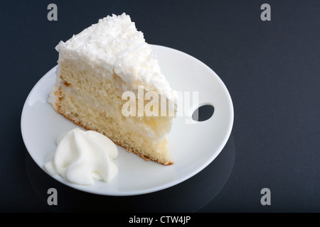 Une nouvelle tranche de gâteau à la crème de noix de coco sur une plaque blanche. Banque D'Images