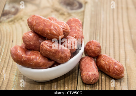 Un tas de mini saucissons sur fond de bois Banque D'Images