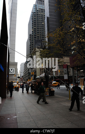 Trottoir de l'automne, portrait de la 7e Avenue, man holding raclette télescopique façade nettoyage Chase Bank, West 52nd Street, New York Banque D'Images