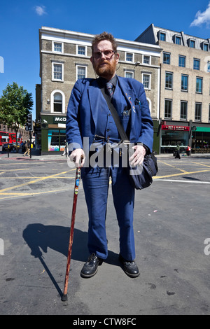 Portrait complet d'un homme barbu debout avec une canne sur un trottoir, Londres, Angleterre, Royaume-Uni. Banque D'Images