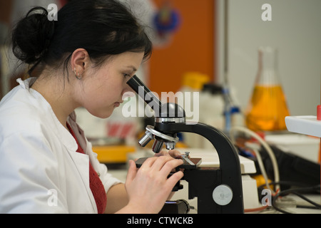 Jeune femme en laboratoire d'université travaille avec microscope Banque D'Images