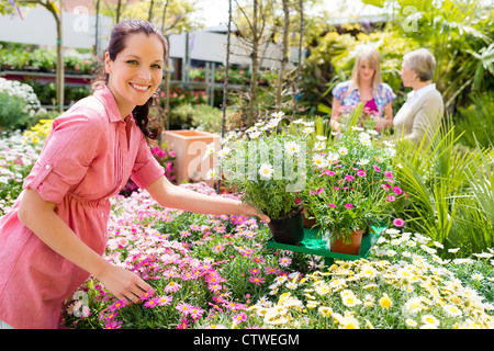 L'organisation de pots de fleurs fleuriste souriant en jardinerie magasin serre Banque D'Images