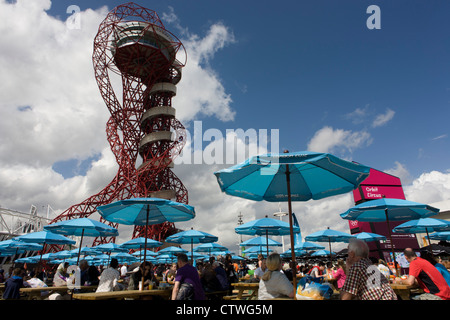 Spectateurs reste dans brolleys de marque et de l'œuvre d'art connue sous le nom de la tour de l'orbite dans le Parc olympique au cours de l'Jeux olympiques de 2012 à Londres. L'article 115 mètres de haut, l'orbite est la plus haute structure de l'art en Grande-Bretagne - offrant une vue sur le stade olympique, le Parc Olympique et l'ensemble de Londres. Situé en orbite Circus dans le sud du Parc olympique, l'orbite est de Londres nouvelle grande destination touristique par l'artiste Anish Kapoor. Banque D'Images