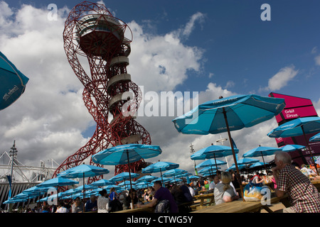 Spectateurs reste dans brolleys de marque et de l'œuvre d'art connue sous le nom de la tour de l'orbite dans le Parc olympique au cours de l'Jeux olympiques de 2012 à Londres. L'article 115 mètres de haut, l'orbite est la plus haute structure de l'art en Grande-Bretagne - offrant une vue sur le stade olympique, le Parc Olympique et l'ensemble de Londres. Situé en orbite Circus dans le sud du Parc olympique, l'orbite est de Londres nouvelle grande destination touristique par l'artiste Anish Kapoor. Banque D'Images