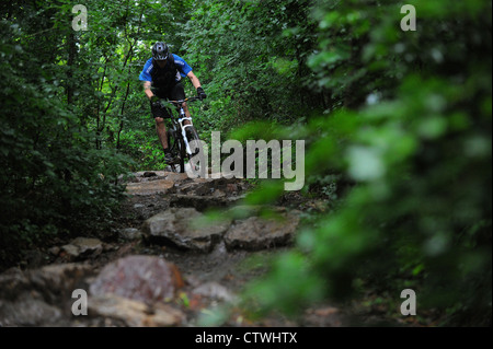 Un vélo de montagne monte un sentier rocheux à Ashton Court à Bristol. Banque D'Images