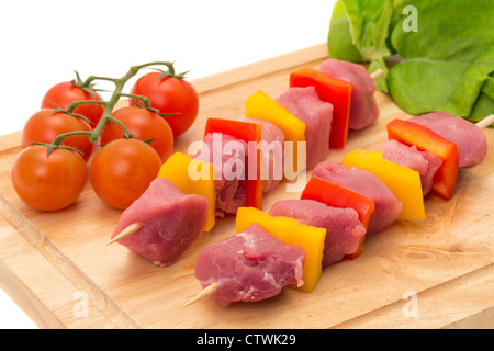 Brochettes de porc fraîchement préparés kebab sur une planche à découper en bois - studio photo avec un fond blanc Banque D'Images